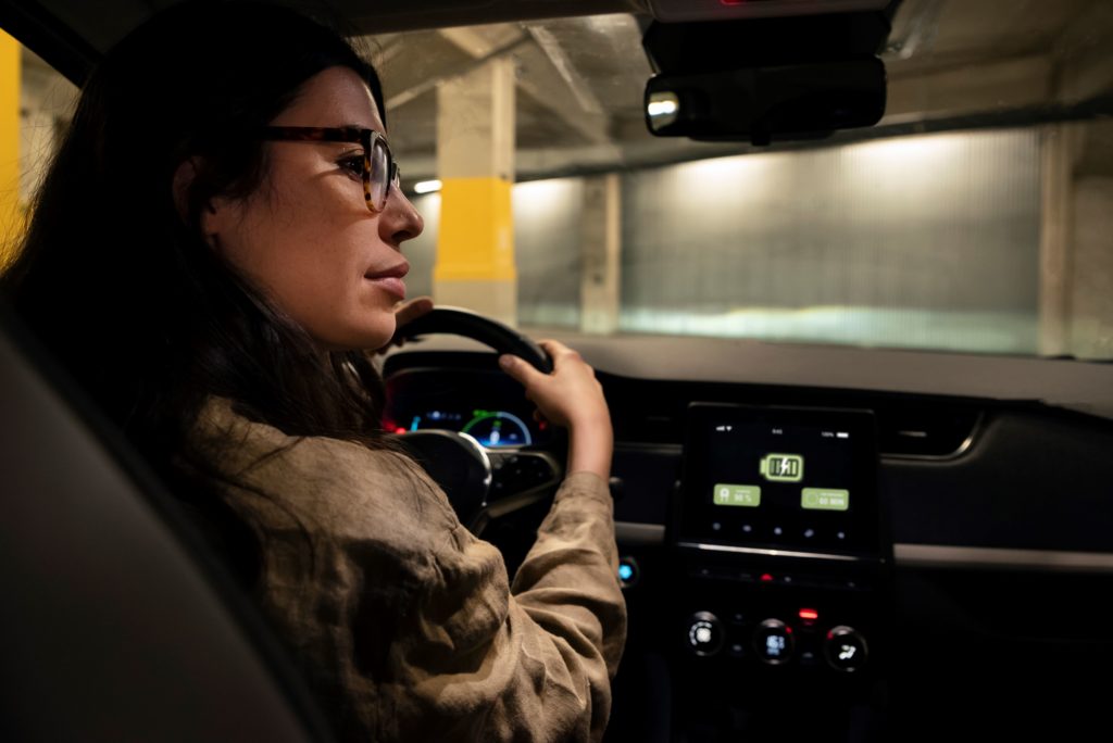 femme au volant d'une voiture dans un parking la nuit