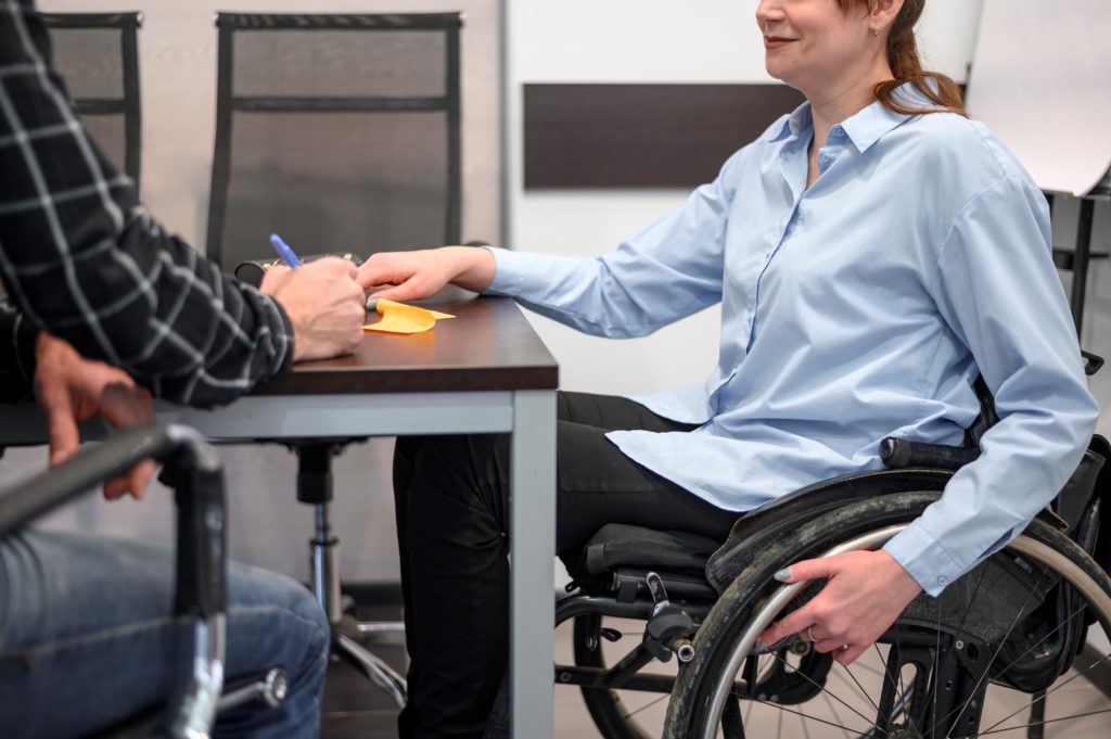 femme assise dans un fauteuil roulant derrière bureau