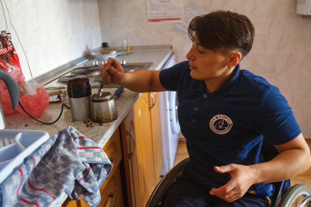 Femme en fauteuil roulant se préparant un café dans sa cuisine
